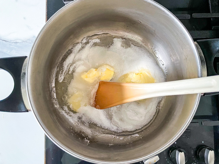 Saucepan with sugar, butter, and glucose syrup and a spoon
