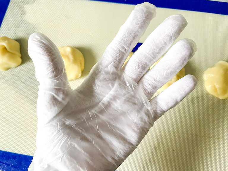 A hand with a cotton glove and a rubber glove over top