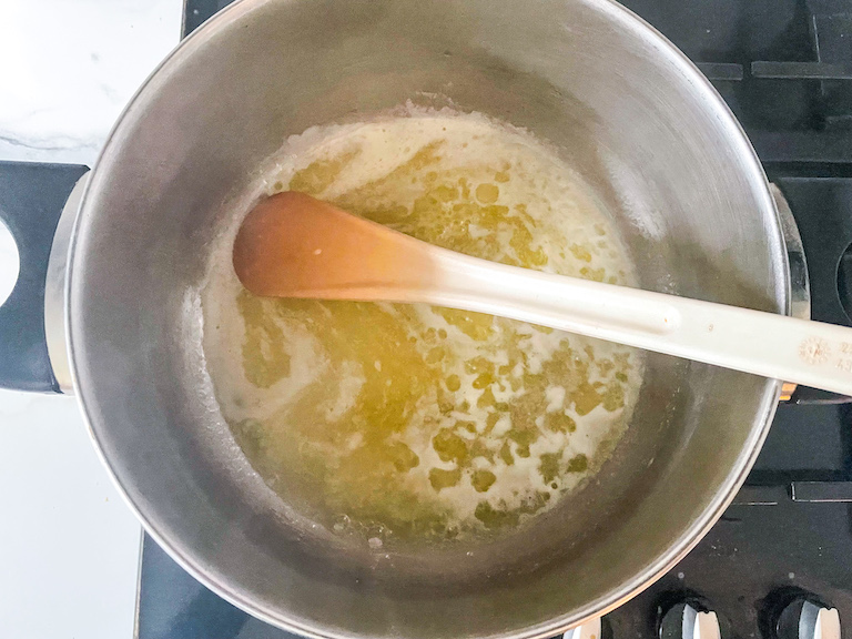 Melted butter and spoon in a pot on the stovetop