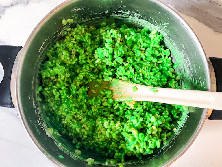 Green rice krispies in a metal pan with a spoon