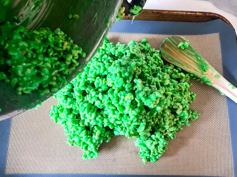 Pouring green rice krispies onto a silicone mat
