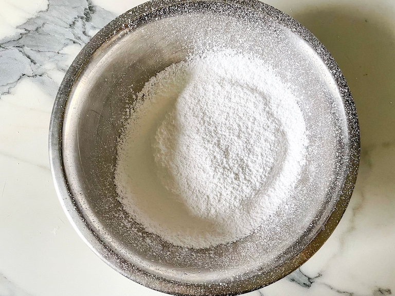 Sifted powdered sugar in a metal bowl