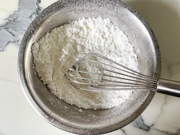 A bowl of sugar and milk powder in a bowl with a whisk