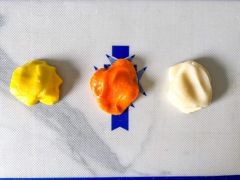 Balls of yellow, orange, and white dough for making homemade candy corn from scratch