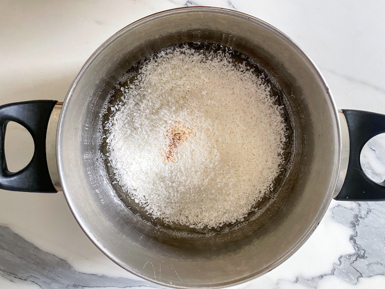 Shredded coconut and flavoring in a large pot with hot sugar mixture
