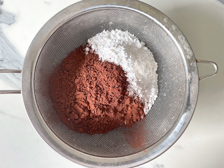 Cocoa powder and confectioner's sugar in a mesh sieve