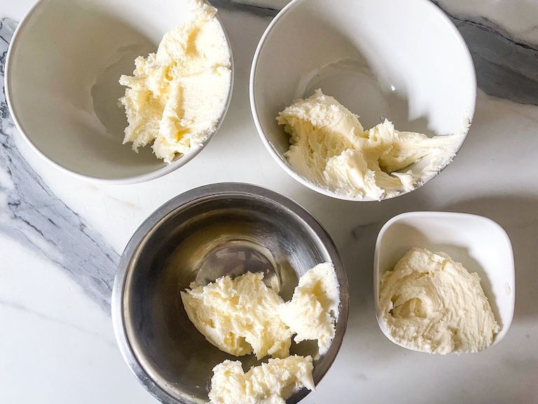 Bowls of white buttercream on a marble countertop