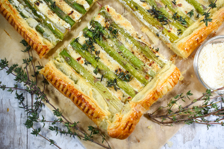 A square of asparagus puff pastry and fresh thyme sprigs on a sheet of parchment