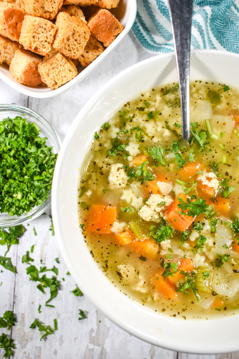 A bowl of no chicken noodle soup, parsley, and croutons