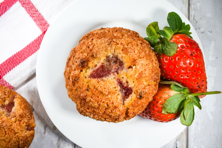 Strawberry muffin on a plate with two red berries