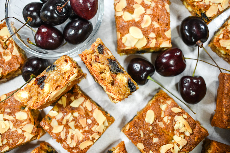Almond butter blondies and fresh cherries on a white surface