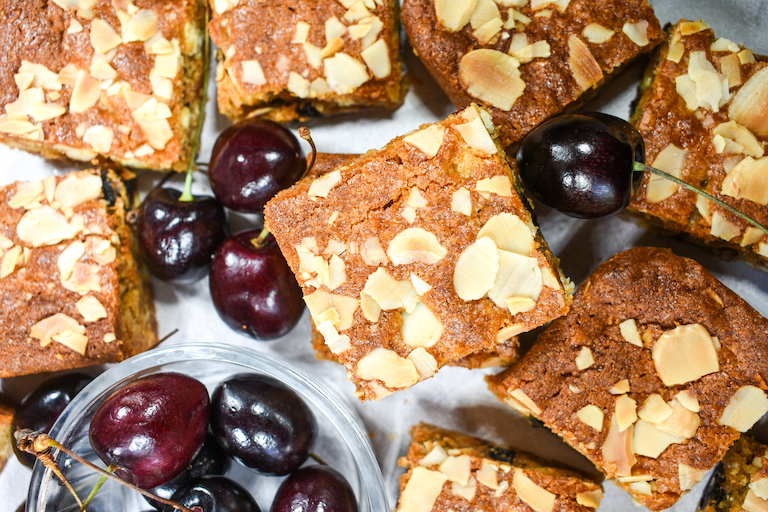 Almond blondies and cherries on a white surface