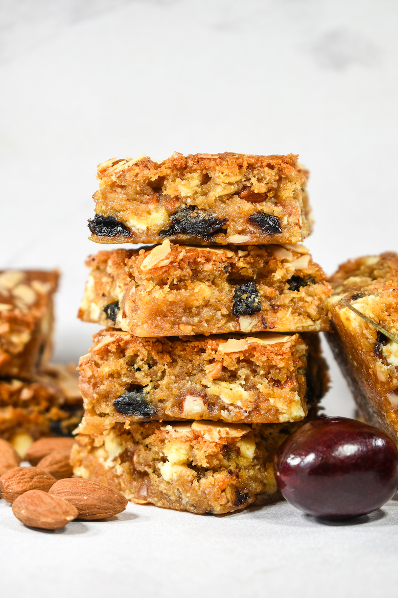 a stack of cherry almond blondies against a white background
