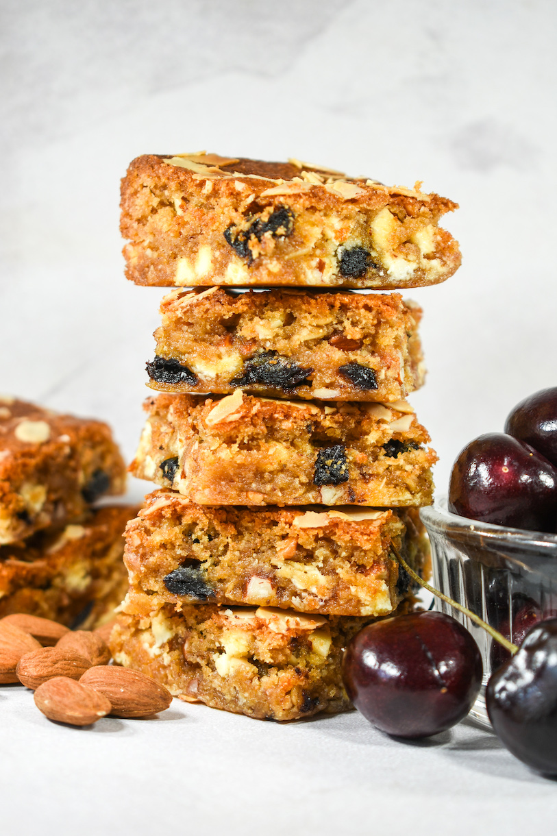 A stack of blondies, almonds, and a bowl of cherries