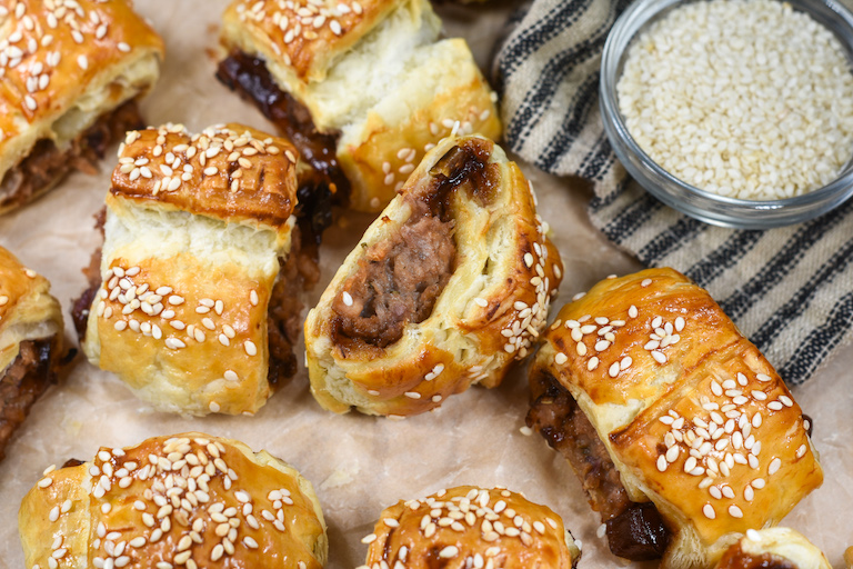 Meatless sausage rolls,a striped towel, and bowl of sesame seeds