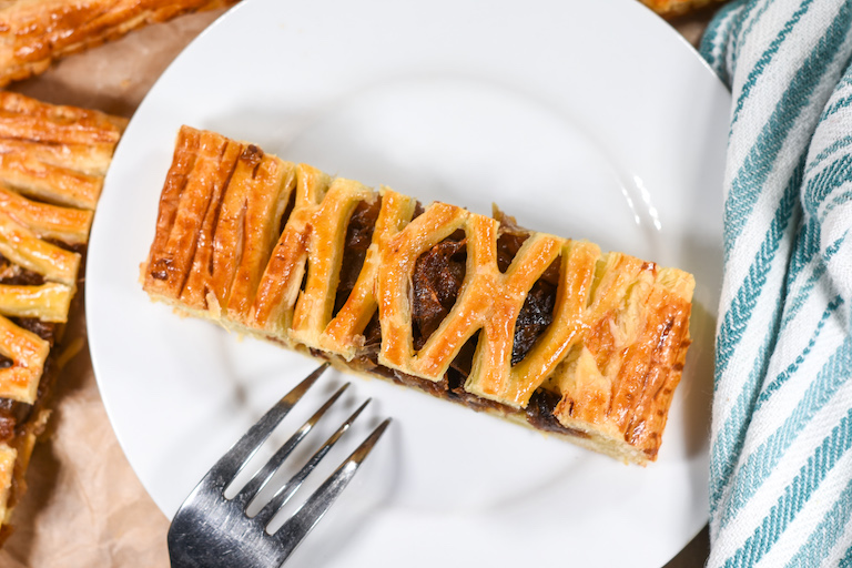 A slice of caramelized onion lattice pastry with a fork