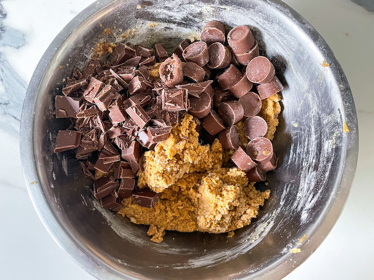 Cookie dough in bowl with chopped chocolate and Rolo candy