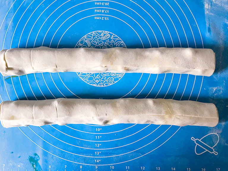 Two tubes of puff pastry on a blue mat