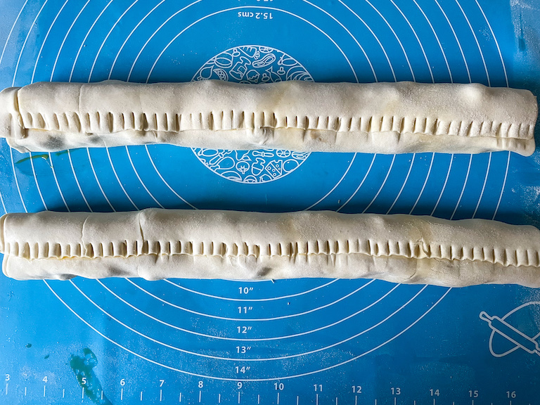 Two tubes of puff pastry with edges crimped by a fork