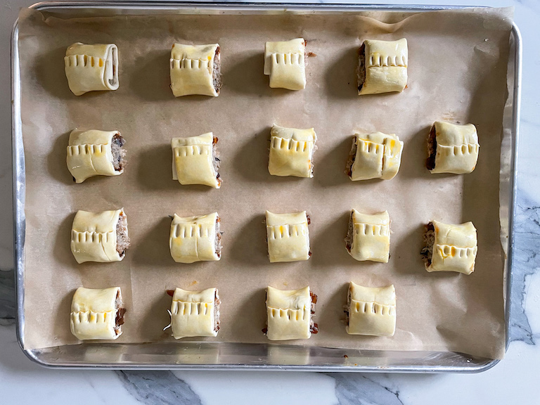 Unbaked sausage rolls arranged on a tray