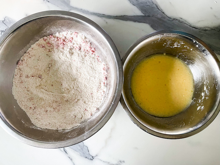 A bowl of dry ingredients and a bowl of wet ingredients on a marble countertop