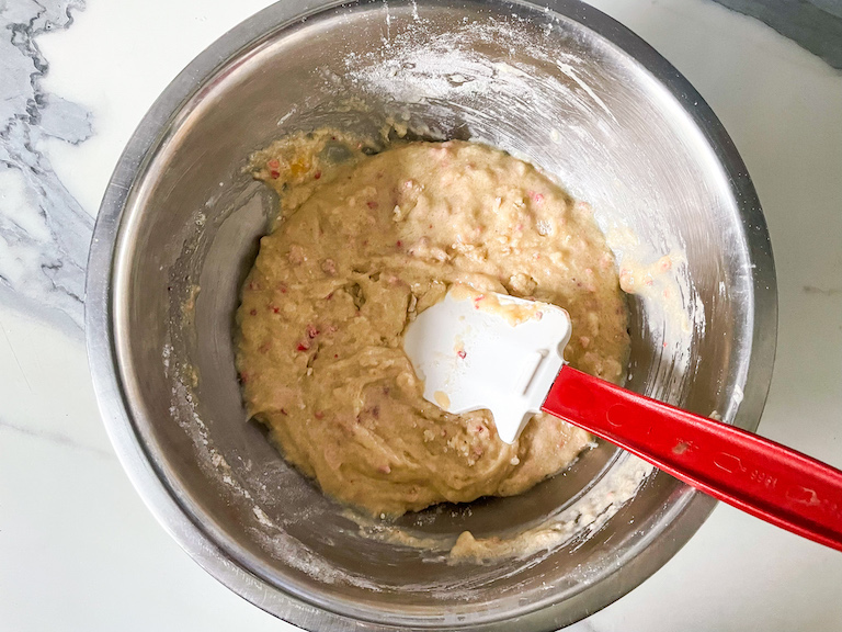 Muffin batter in a metal bowl with a spatula