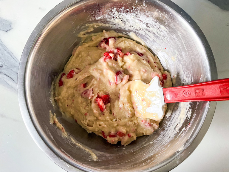 Strawberry muffin batter and a spatula in a metal bowl