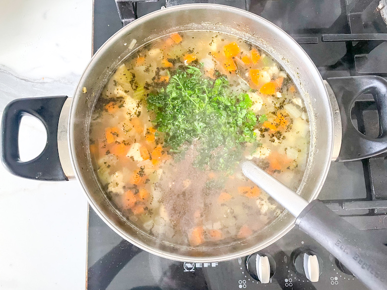 Stirring parsley into chicken noodle soup without chicken