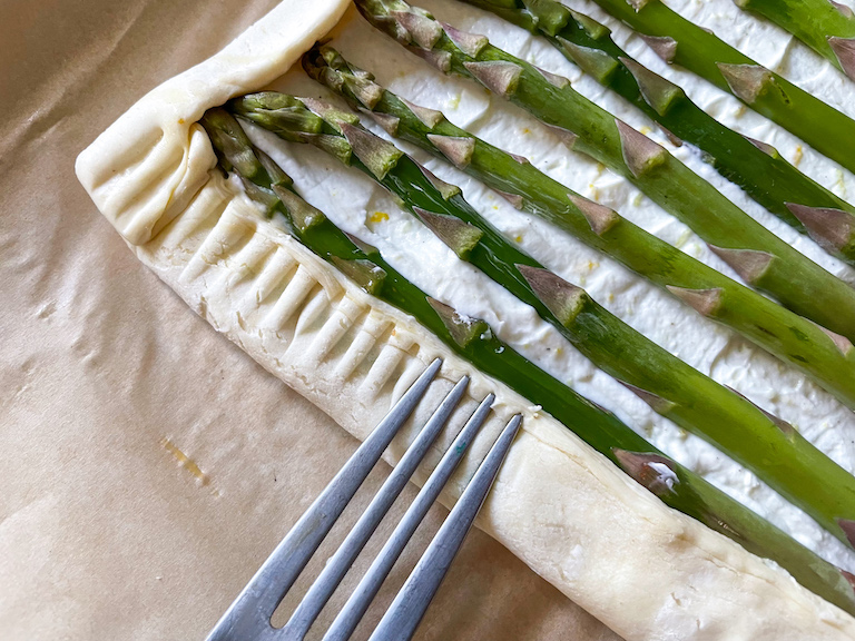 Fork crimping edges of asparagus puff pastry