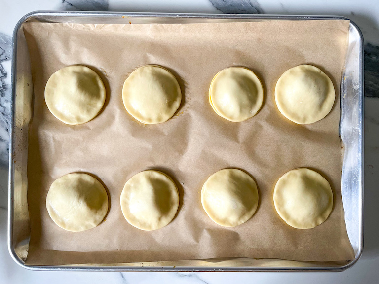 Unbaked hand pies on a parchment lined tray