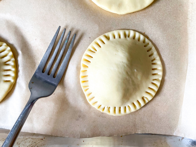 Pastry hand pie with crimped edges and a fork