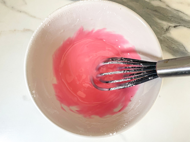 Pink glaze in a bowl with whisk