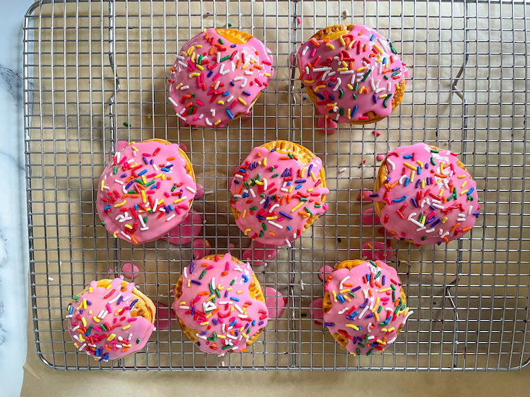 Mini strawberry pies with pink frosting and rainbow sprinkles