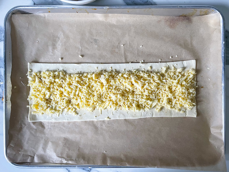 Grated cheese arranged on a rectangle of puff pastry