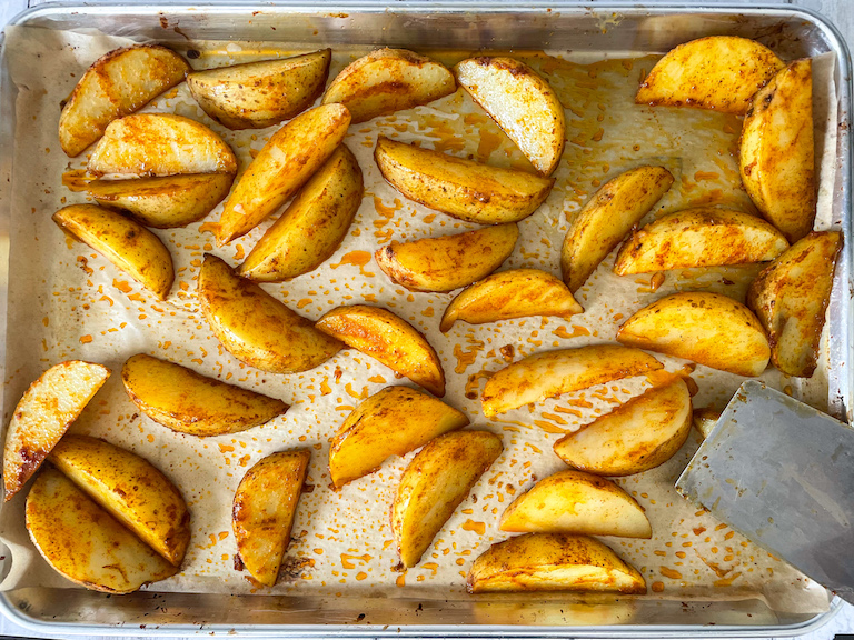 Potato wedges on a tray with a spatula