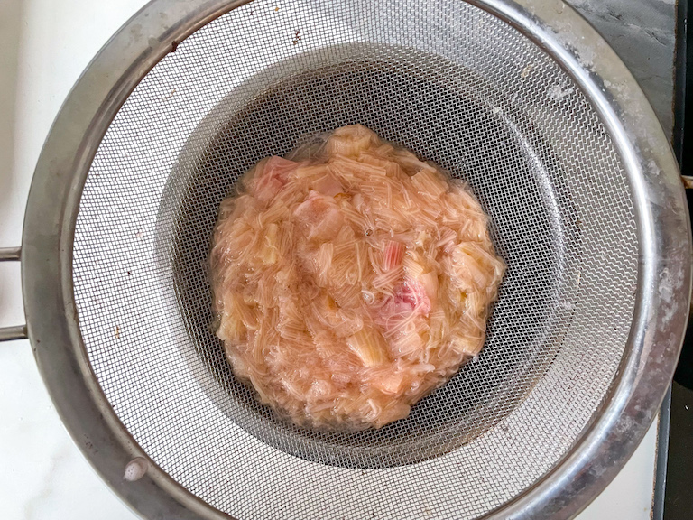 Cooked rhubarb in a mesh strainer