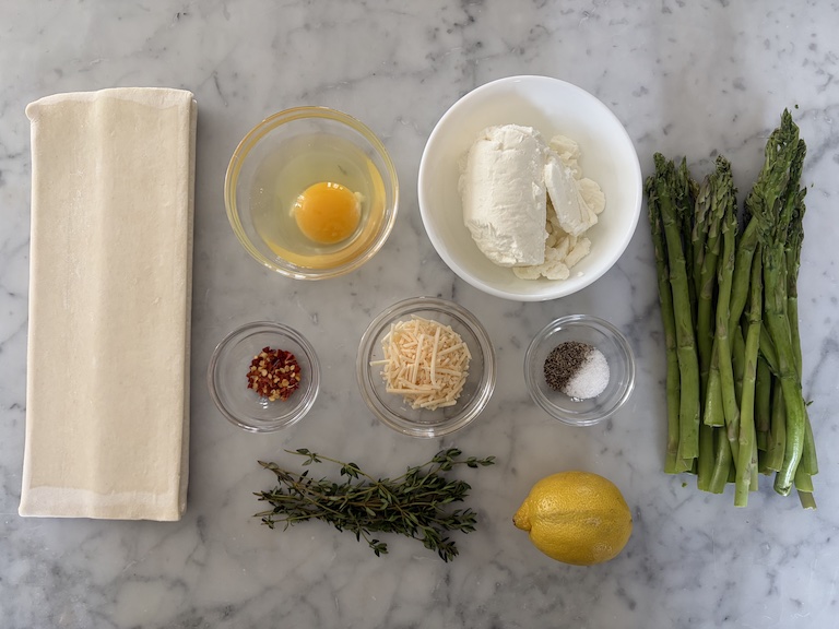 Asparagus puff pastry tart ingredients on a marble surface