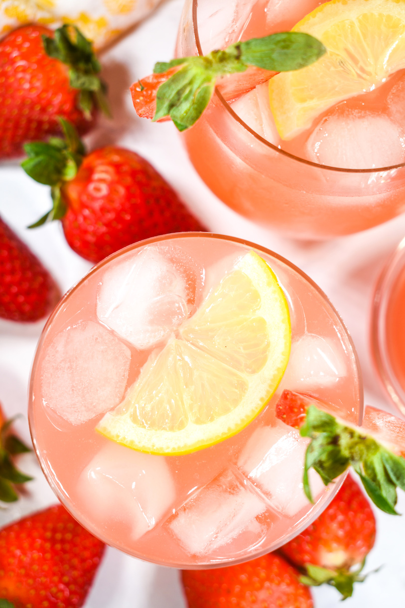 Glass of strawberry rhubarb lemonade with ice and a slice of lemon