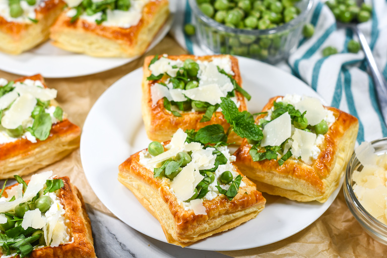Miniature tarts with peas and mint on a white plate