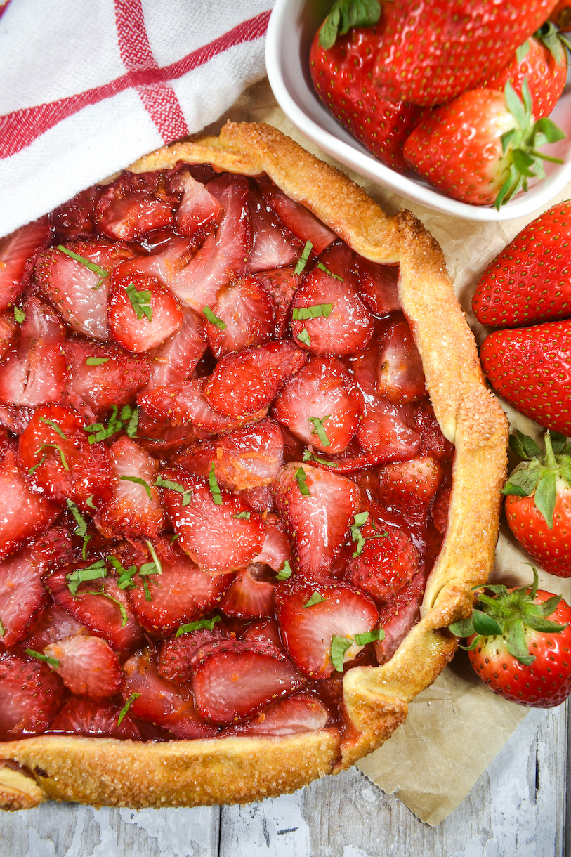 Berry galette surrounded by fresh strawberries
