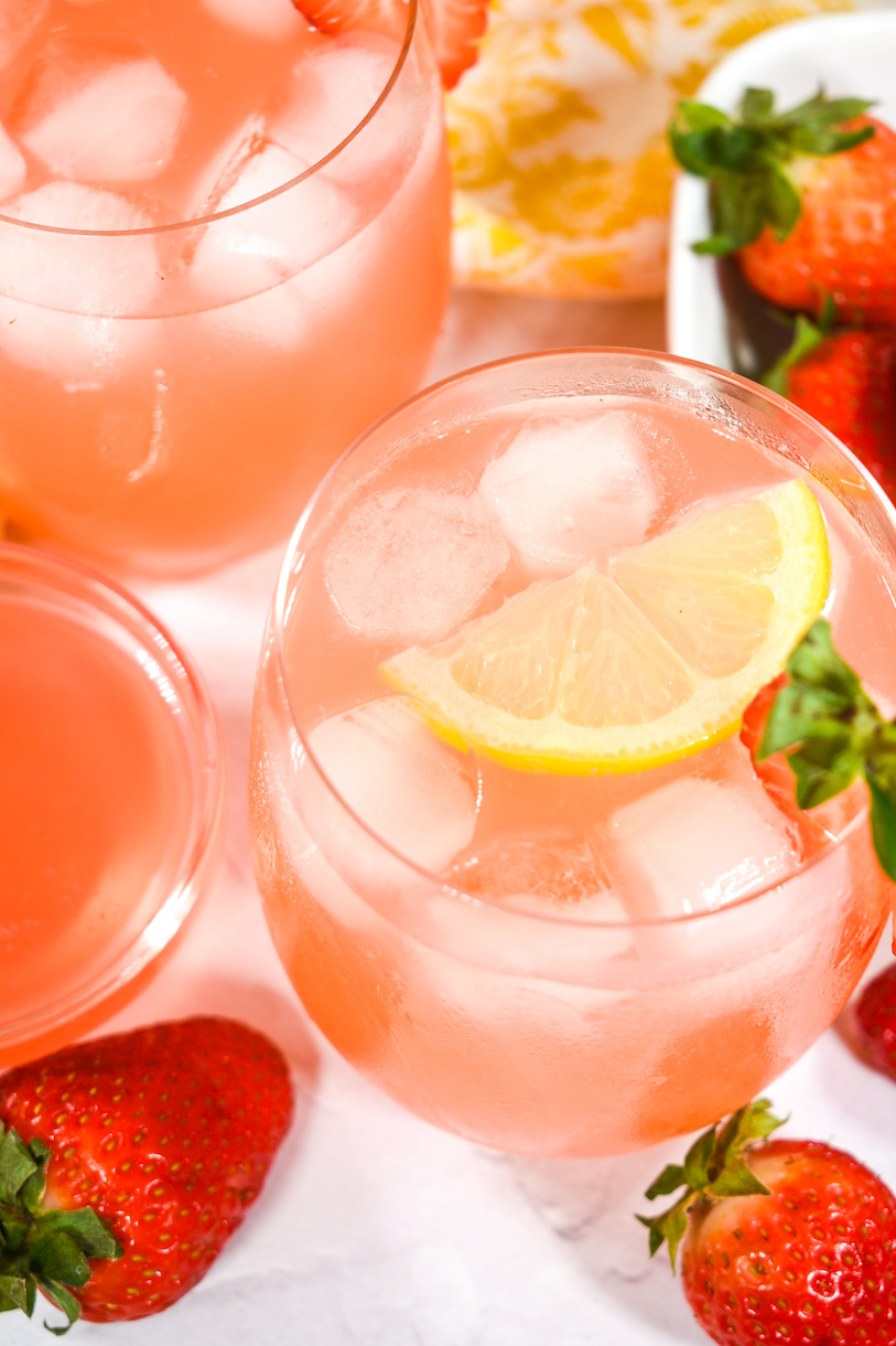 Glasses of rhubarb and strawberry lemonade with lemon slices and berries
