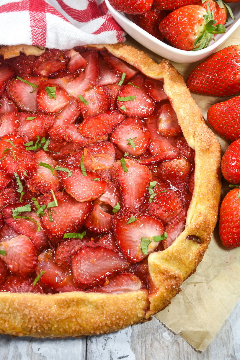 Galette surrounded by fresh berries, on a sheet of parchment