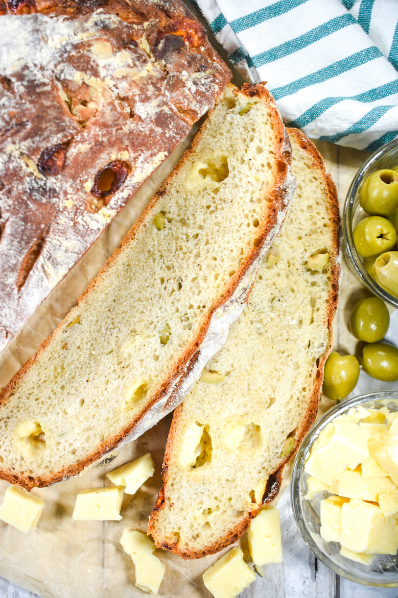 sliced olive bread next to bowls of olives and cheese