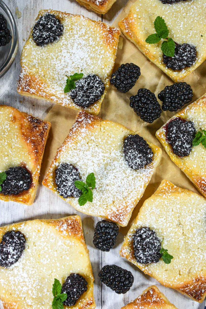 Blackberry goat cheese pastries arranged on parchment with fresh blackberries