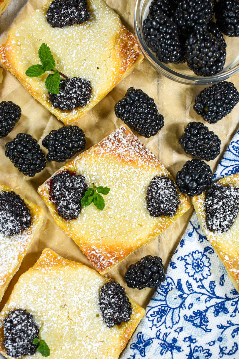 blackberry pastries arranged on a sheet of parchment with fresh blackberries