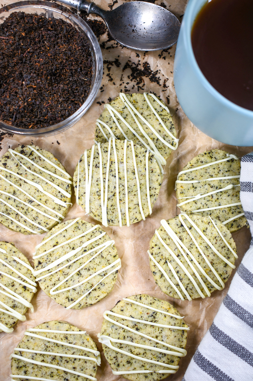 Earl Grey lemon cookies arranged on parchment with a cup of tea and dish of loose tea leaves