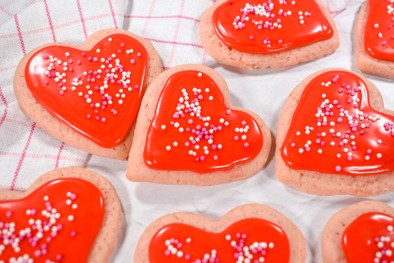 Heart shaped sugar cookies with red frosting and sprinkles