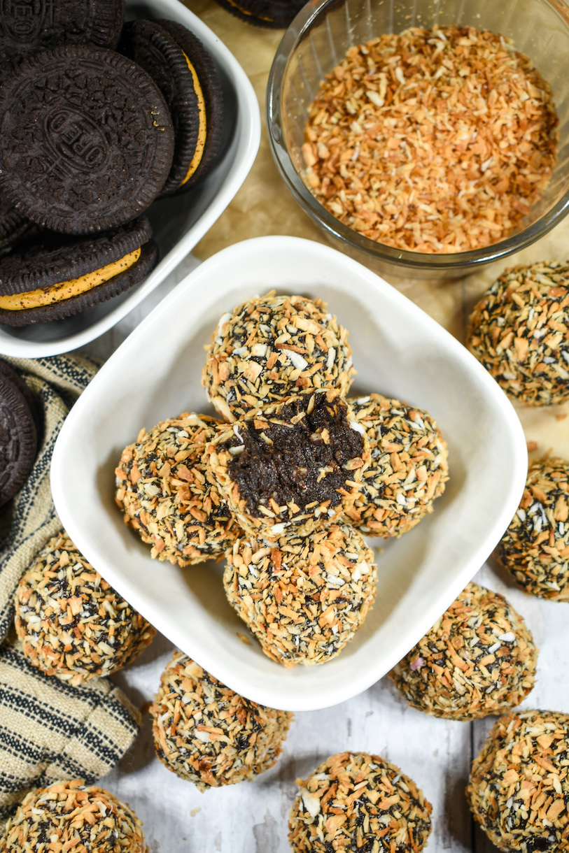 Dish of Oreo truffles, surrounded by cookies, truffles, and dish of toasted coconut