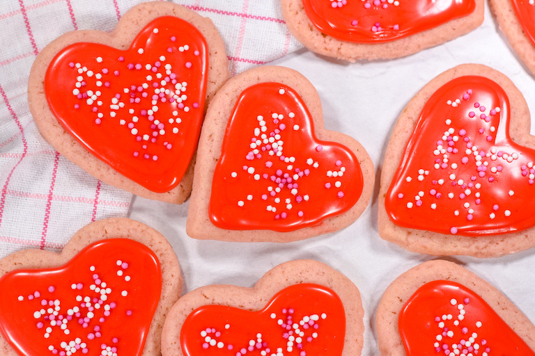 Heart shaped sugar cookies with red icing and sprinkles