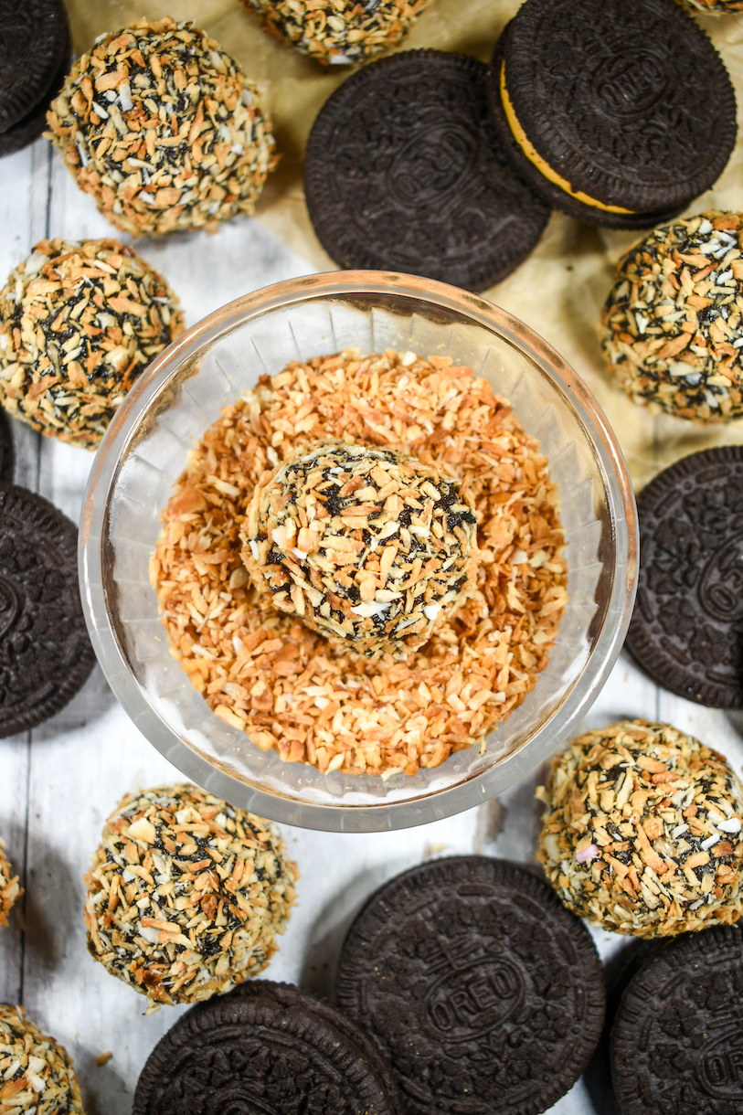 Dish of toasted coconut with an Oreo ball, surrounded by cookies and truffles
